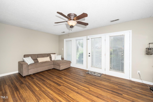 unfurnished living room with visible vents, a textured ceiling, wood finished floors, baseboards, and ceiling fan