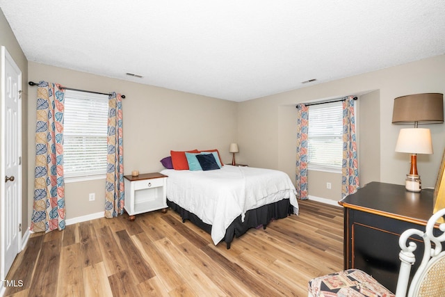 bedroom with multiple windows, baseboards, visible vents, and light wood-type flooring