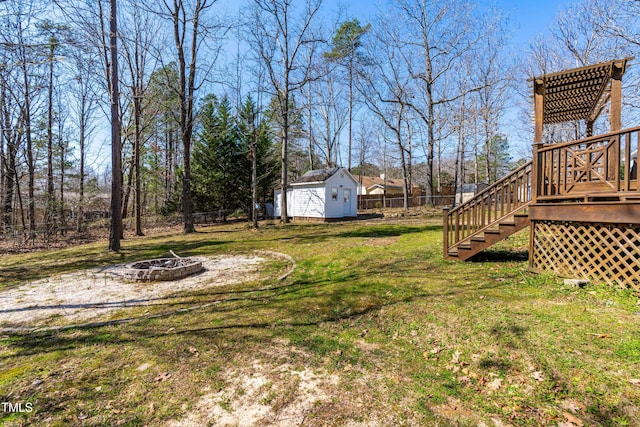 view of yard with an outbuilding, fence, an outdoor fire pit, stairway, and a storage shed