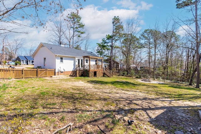 view of yard with a deck, stairs, a fenced backyard, and an outdoor fire pit