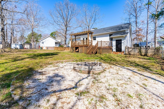 rear view of house with a fire pit, stairway, a lawn, a fenced backyard, and a deck