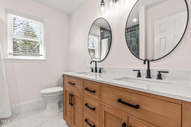 bathroom with toilet, baseboards, marble finish floor, and a sink