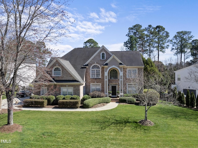 view of front of house featuring brick siding, a front lawn, and a shingled roof