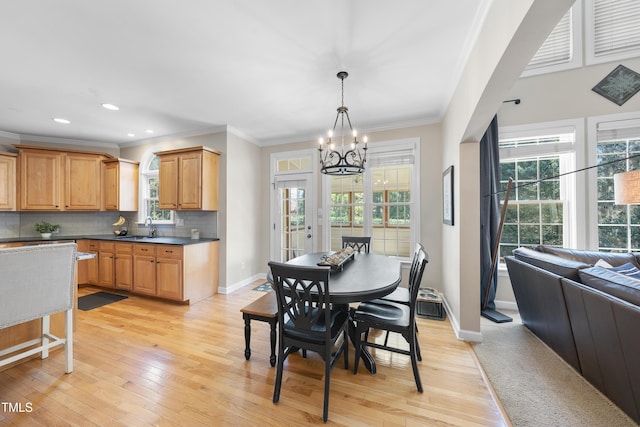 dining room featuring an inviting chandelier, a healthy amount of sunlight, crown molding, and light wood finished floors