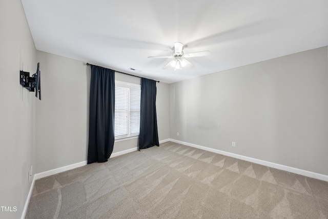 empty room featuring light carpet, visible vents, baseboards, and ceiling fan