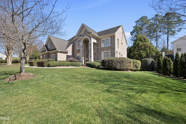 greek revival inspired property featuring brick siding and a front yard