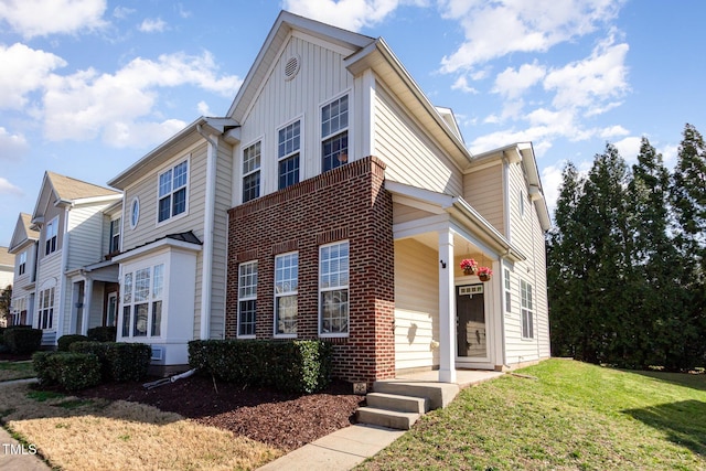 view of front of property featuring brick siding, board and batten siding, and a front yard