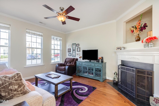 living area featuring visible vents, crown molding, a fireplace with flush hearth, and wood finished floors