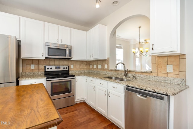 kitchen with a sink, wood finished floors, appliances with stainless steel finishes, butcher block counters, and decorative backsplash