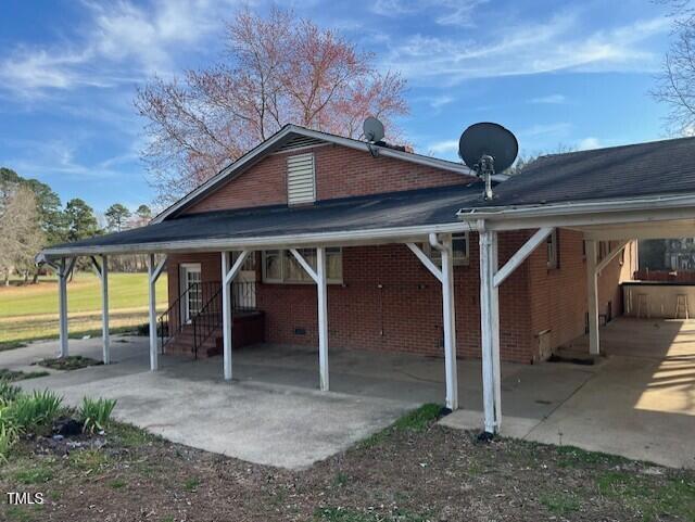 rear view of property with an attached carport and brick siding