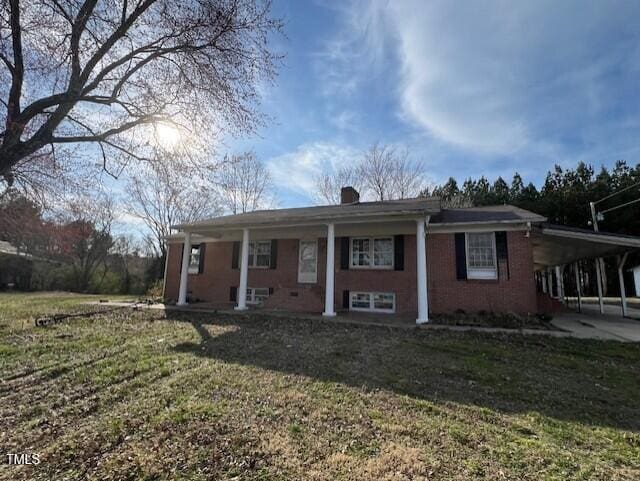 view of front facade featuring brick siding, driveway, a carport, and a front lawn