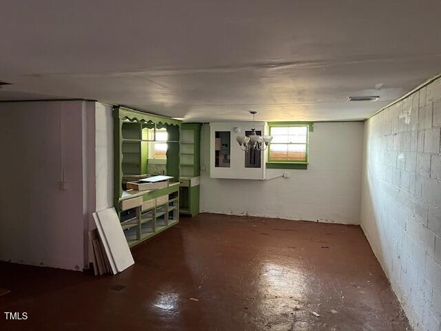 unfurnished room featuring visible vents, concrete floors, and concrete block wall