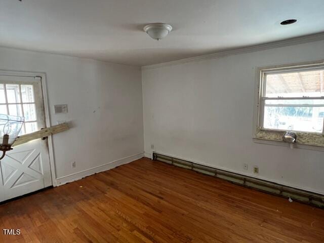 unfurnished room with a wealth of natural light, a baseboard heating unit, baseboards, and wood finished floors