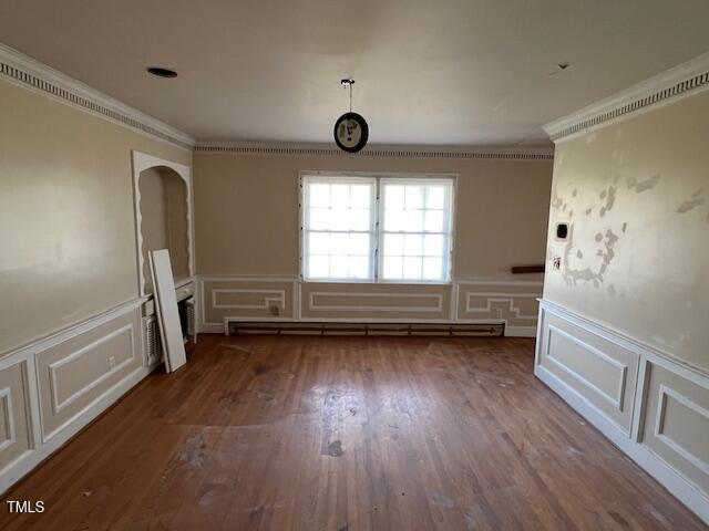 unfurnished room with a decorative wall, ornamental molding, wood finished floors, and a baseboard radiator