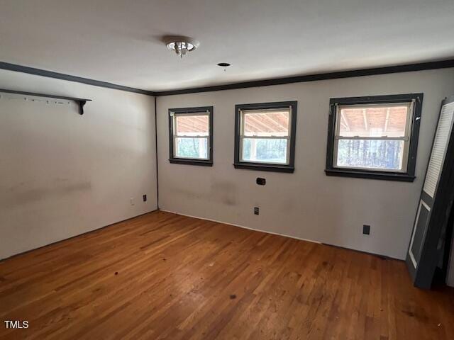 spare room featuring wood finished floors and crown molding