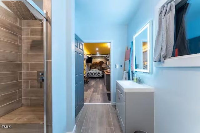 full bathroom with wood finished floors, vanity, and a tile shower