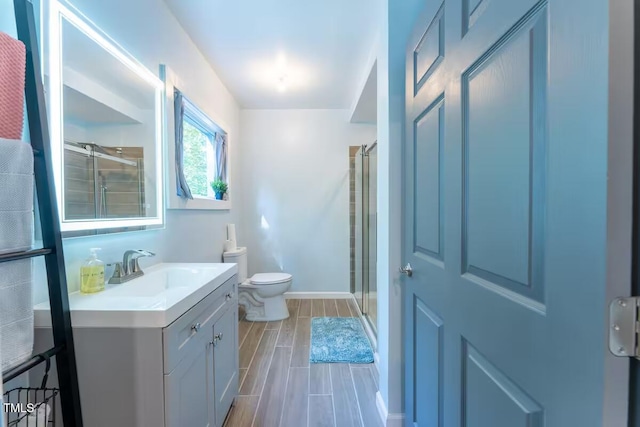 bathroom with vanity, toilet, a stall shower, and wood tiled floor