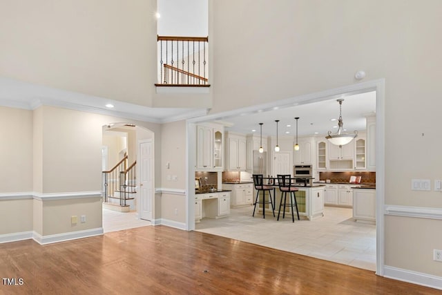 405 Silver Creek Trl, Chapel Hill, NC 27514 - living area with arched walkways, light wood-style floors, a high ceiling, stairs, and recessed lighting