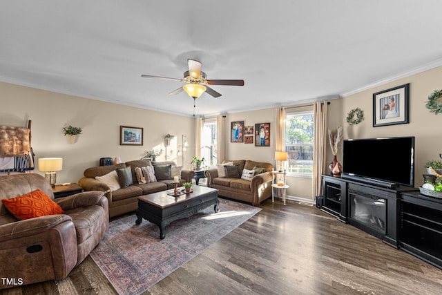 living area with ornamental molding, baseboards, a ceiling fan, and dark wood-style flooring