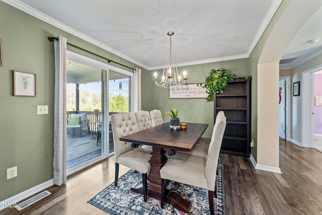 dining room featuring baseboards, wood finished floors, visible vents, and ornamental molding