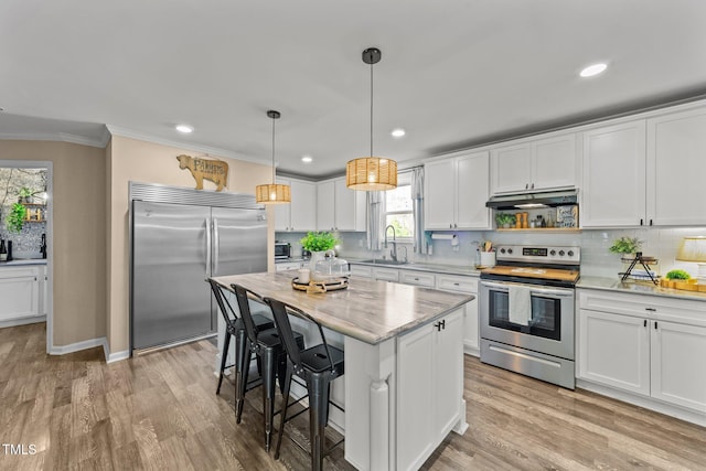 kitchen featuring a sink, under cabinet range hood, appliances with stainless steel finishes, crown molding, and backsplash