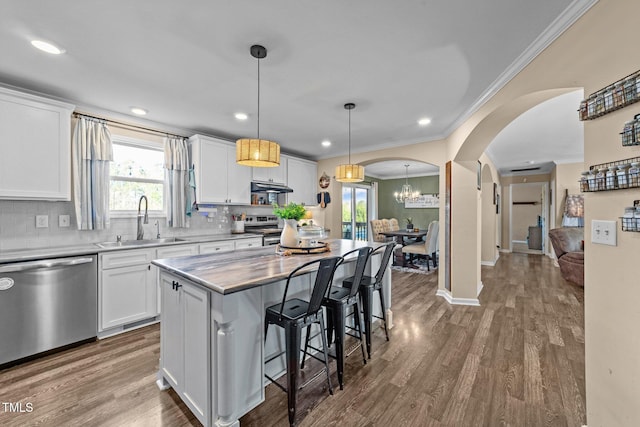 kitchen with dark wood-type flooring, a kitchen bar, arched walkways, stainless steel appliances, and a sink