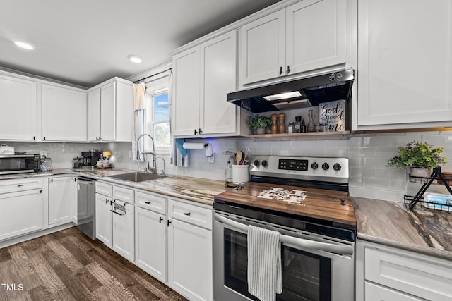 kitchen with dark wood-type flooring, under cabinet range hood, a sink, stainless steel appliances, and white cabinets