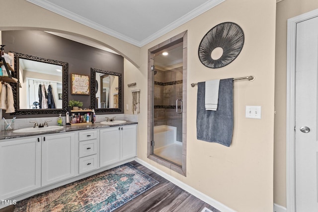 bathroom with a sink, wood finished floors, a shower stall, and crown molding