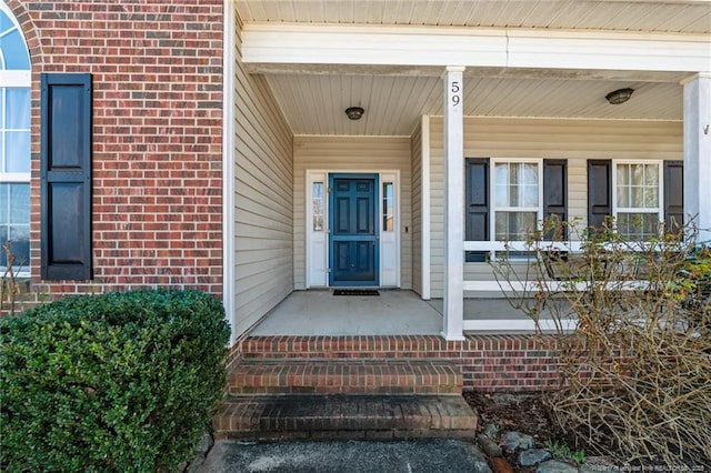 entrance to property with covered porch and brick siding