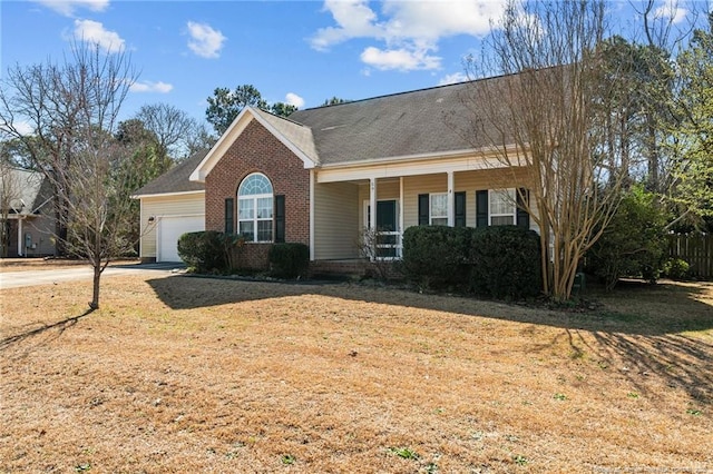 view of front of home featuring a front yard, driveway, covered porch, a garage, and brick siding