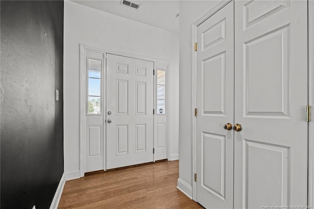 entrance foyer with wood finished floors, visible vents, and baseboards