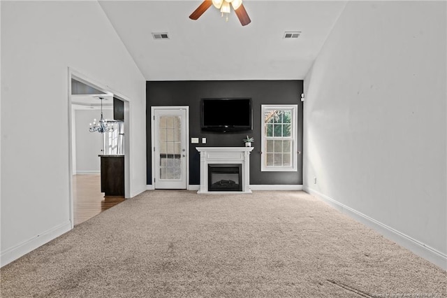 unfurnished living room with visible vents, carpet floors, a fireplace, and ceiling fan with notable chandelier