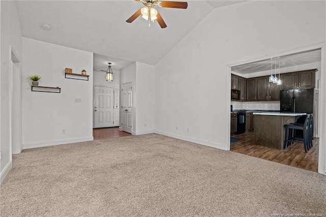 unfurnished living room featuring lofted ceiling, a ceiling fan, baseboards, and carpet floors