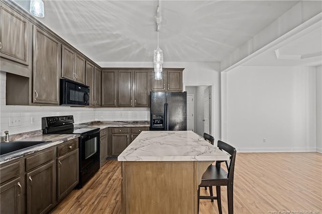 kitchen with tasteful backsplash, black appliances, a breakfast bar, and a center island