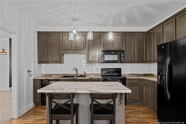 kitchen featuring wood finished floors, dark brown cabinets, black appliances, and a sink