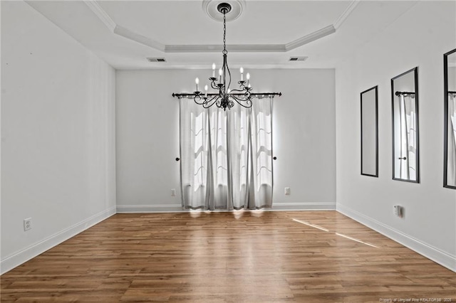 unfurnished dining area featuring a tray ceiling, wood finished floors, visible vents, and a healthy amount of sunlight