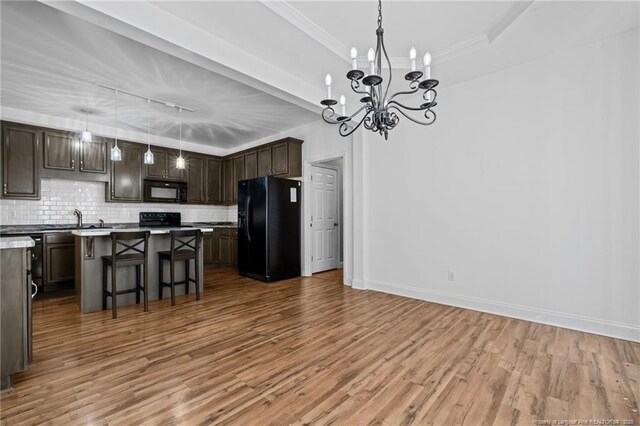 kitchen with decorative backsplash, dark brown cabinets, black appliances, and a raised ceiling