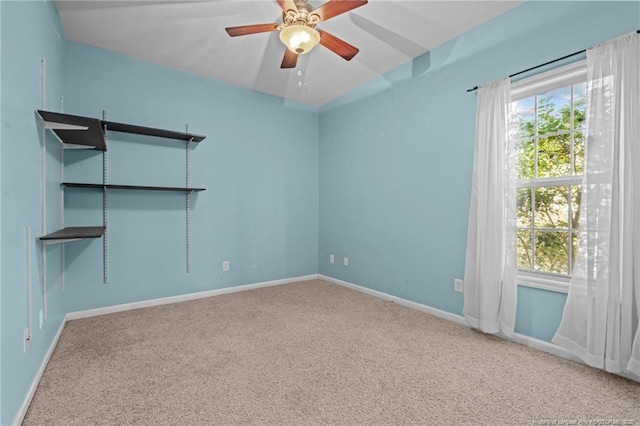 carpeted empty room featuring baseboards and a ceiling fan