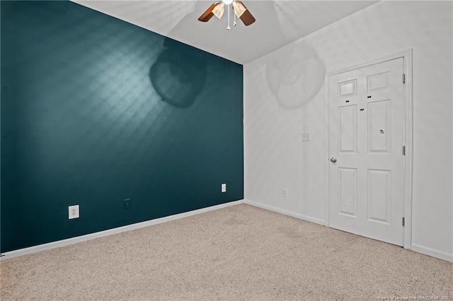 carpeted empty room with a ceiling fan and baseboards