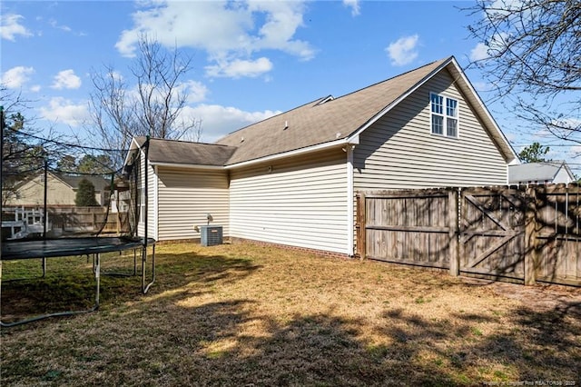 view of side of property featuring a trampoline, fence, and a yard