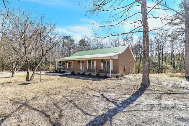 view of front of property featuring brick siding, a porch, and metal roof