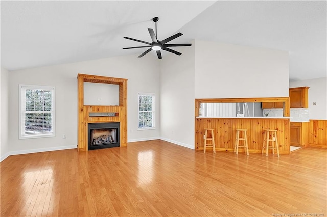 unfurnished living room with a ceiling fan, vaulted ceiling, light wood-style flooring, and a fireplace