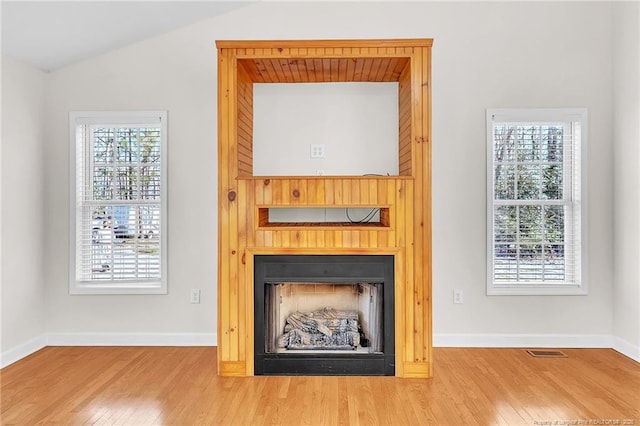 interior details featuring baseboards, wood finished floors, visible vents, and a large fireplace