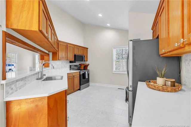 kitchen featuring decorative backsplash, brown cabinets, appliances with stainless steel finishes, and a sink