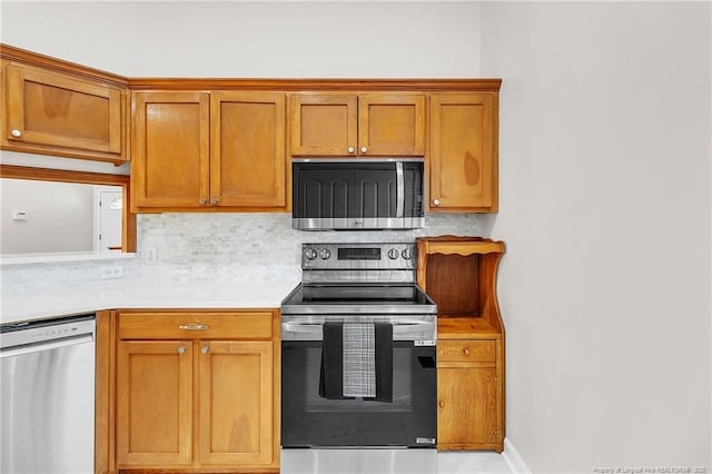 kitchen featuring brown cabinetry, baseboards, stainless steel appliances, light countertops, and tasteful backsplash