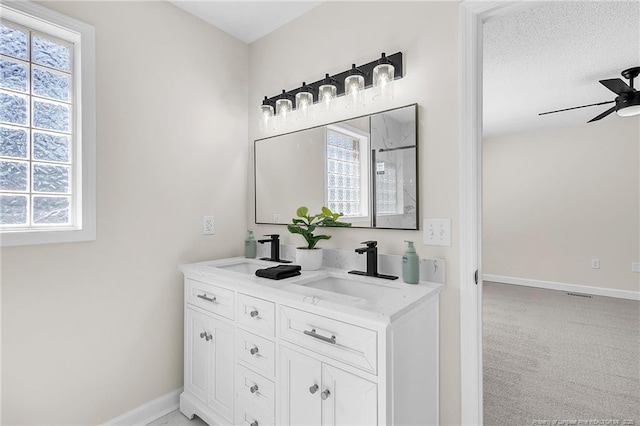 bathroom with double vanity, baseboards, ceiling fan, and a sink