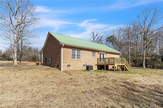 back of house with brick siding, a wooden deck, cooling unit, metal roof, and crawl space