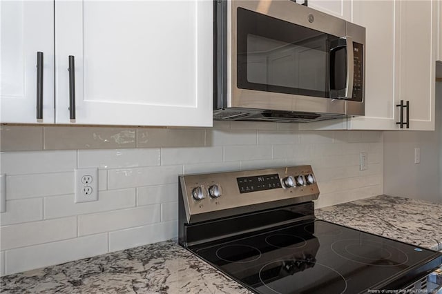 5814 James Allen Ln, Stedman, NC 28391 - kitchen view of appliances with stainless steel finishes, white cabinetry, decorative backsplash, and light stone counters