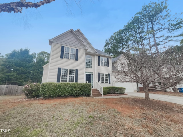 view of front facade featuring a garage, driveway, entry steps, and fence