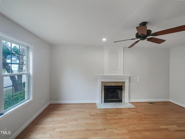 unfurnished living room featuring recessed lighting, baseboards, light wood-type flooring, and a premium fireplace